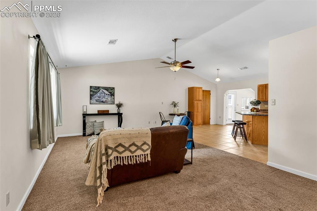 Image 3 of 42: Bedroom with light carpet, baseboards, lofted ceiling, light tile patterned