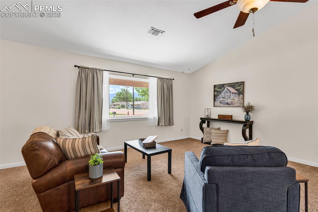 Image 5 of 42: Carpeted living area with a ceiling fan, baseboards, and vaulted ceiling