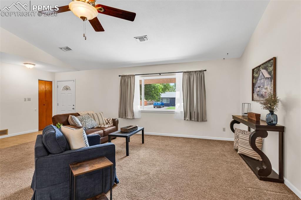 Image 6 of 42: Carpeted living area with vaulted ceiling, a ceiling fan, and baseboards