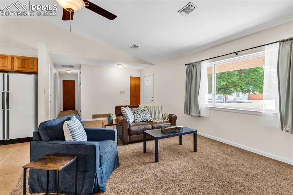 Image 7 of 42: Living room with lofted ceiling, a ceiling fan, and baseboards