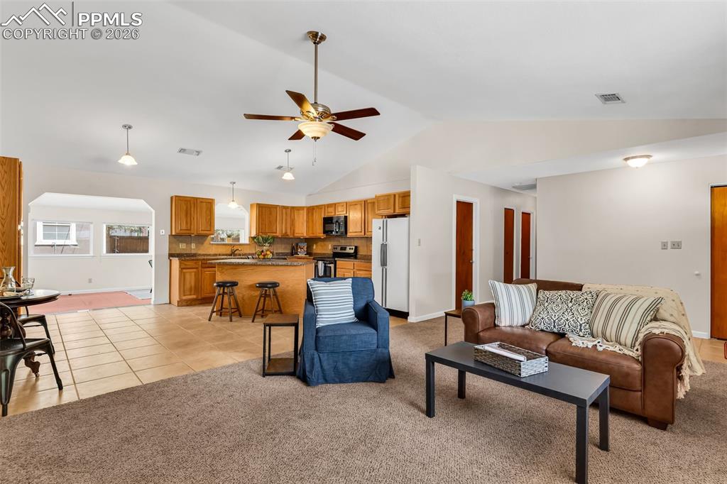 Image 8 of 42: Living room featuring vaulted ceiling, ceiling fan, light colored carpet, a