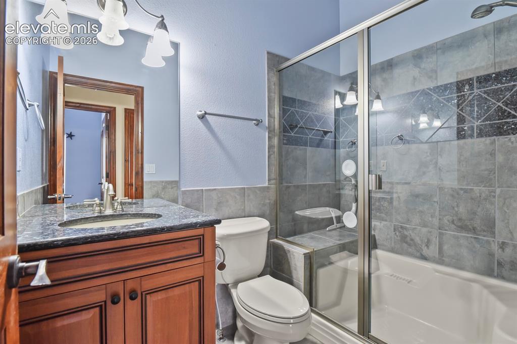Image 15 of 33: Main level bathroom with custom tile and granite