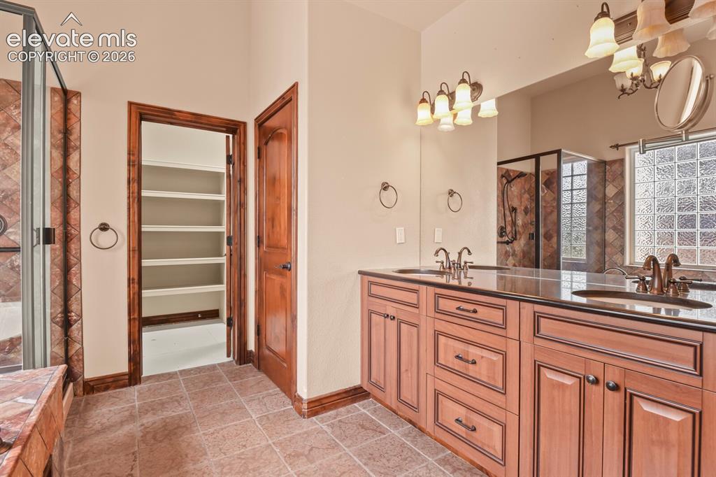Image 18 of 33: Primary bathroom with double sinks, custom cabinets, granite countertops