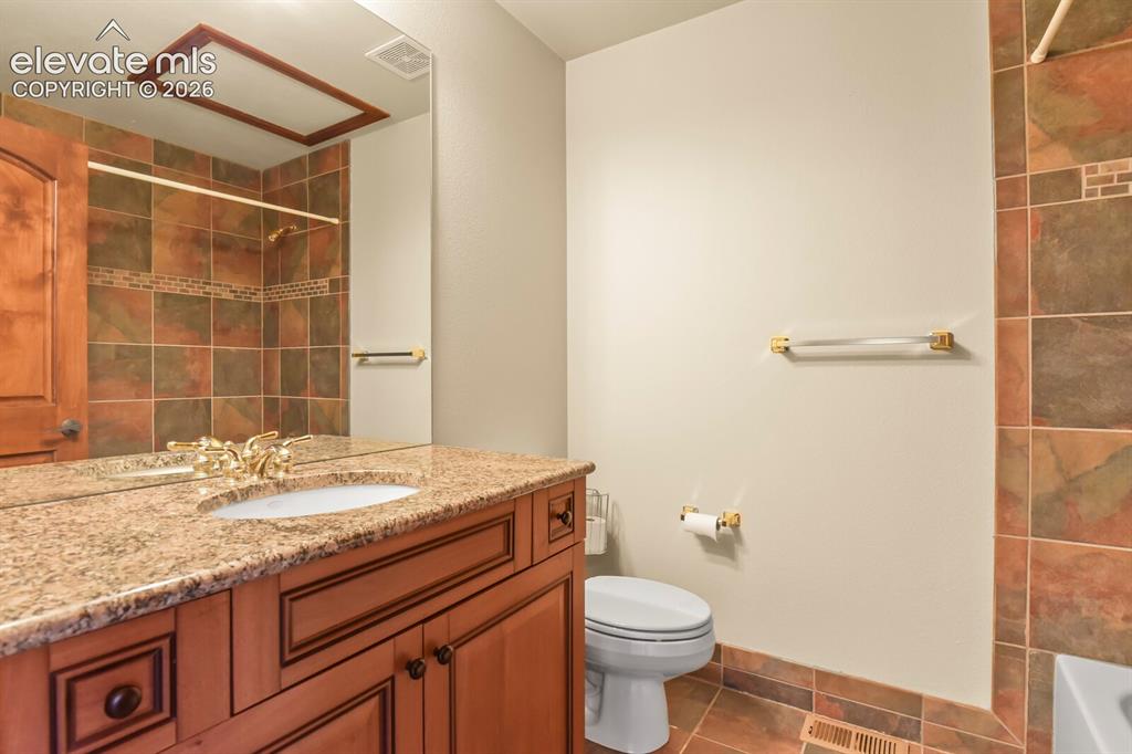 Image 23 of 33: Upper level full bath with the same custom cabinetry and granite sink