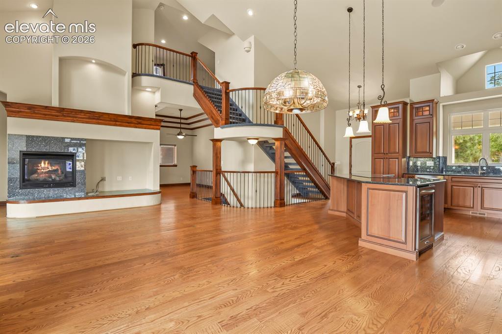 Image 9 of 33: Grand picture of kitchen, staircases, fireplace and gorgeous hardwood floor