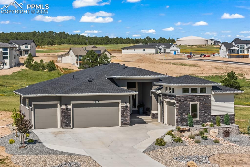 Caption: View of front of property with stone siding and concrete driveway