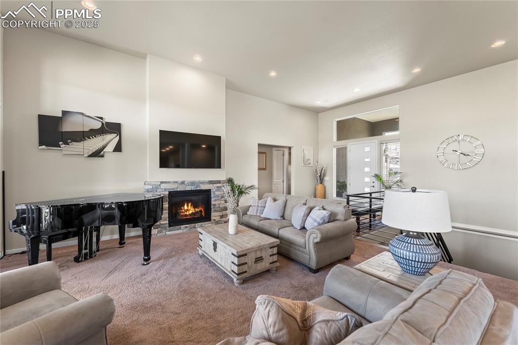 Image 12 of 50: Living area featuring a fireplace, carpet flooring, and recessed lighting