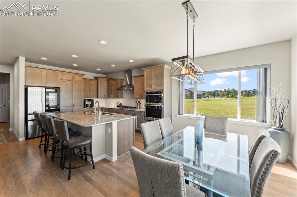 Image 18 of 50: Kitchen with stainless steel appliances, wall chimney range hood, light sto