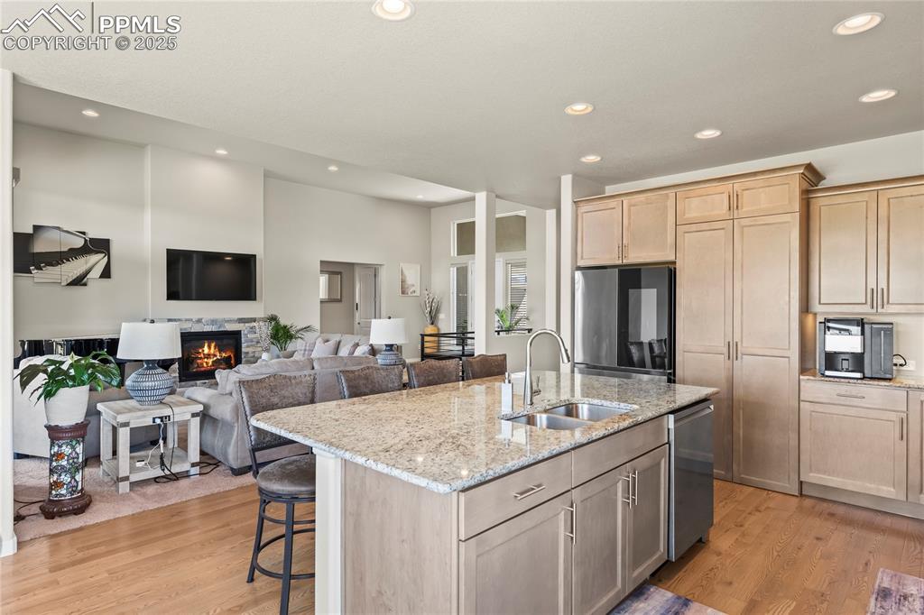Image 19 of 50: Kitchen with refrigerator, dishwasher, light brown cabinetry, light wood-ty