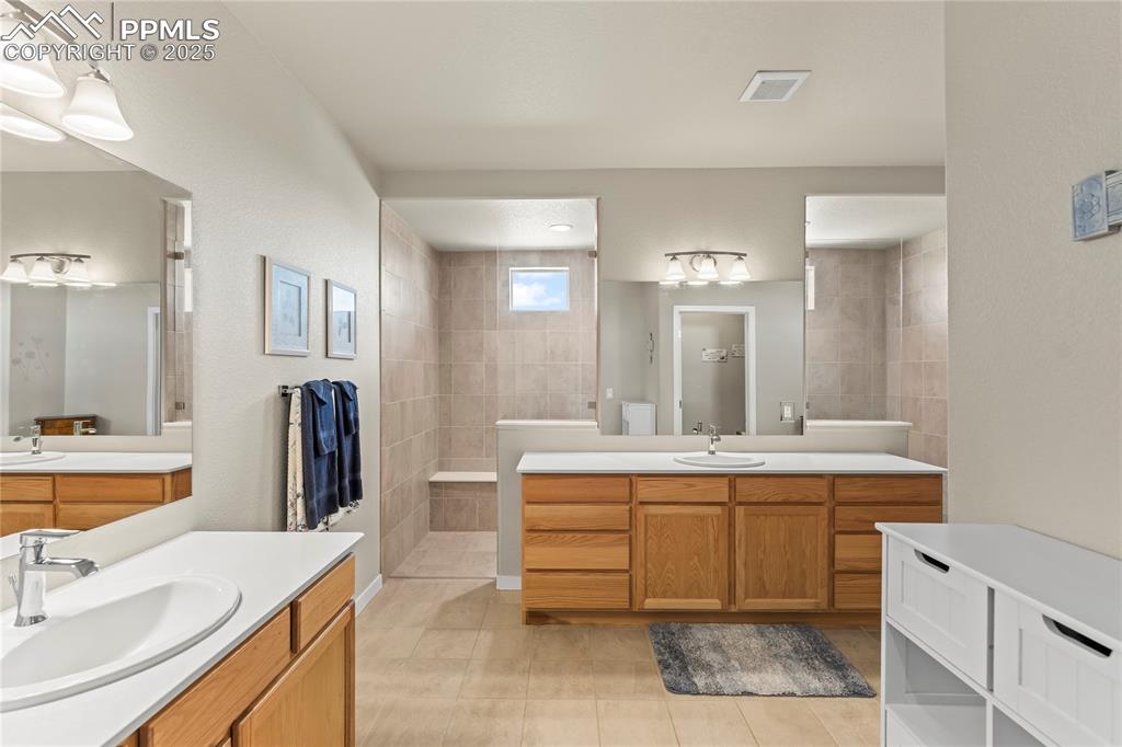 Image 26 of 50: Bathroom featuring walk in shower, tile patterned floors, and two vanities