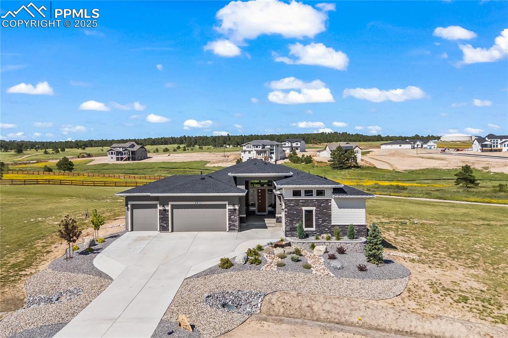 Image 3 of 50: Prairie-style home with stone siding, a garage, and driveway