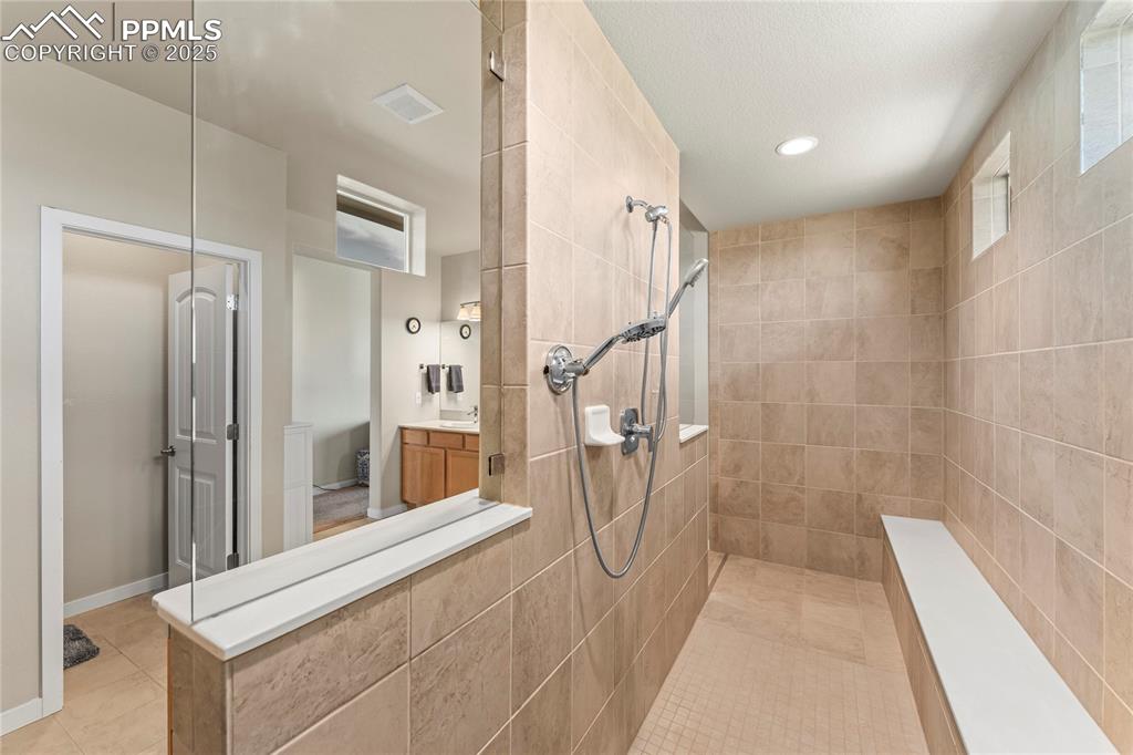 Image 30 of 50: Bathroom with tile patterned floors, walk in shower, vanity, and recessed l