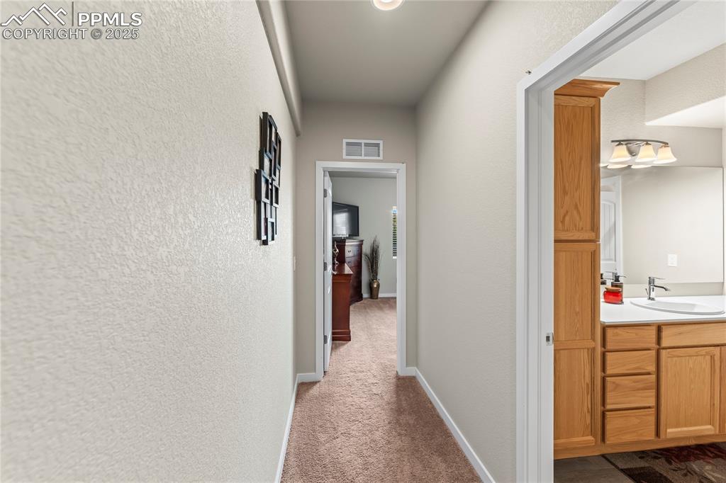 Image 44 of 50: Corridor featuring dark colored carpet and a textured wall