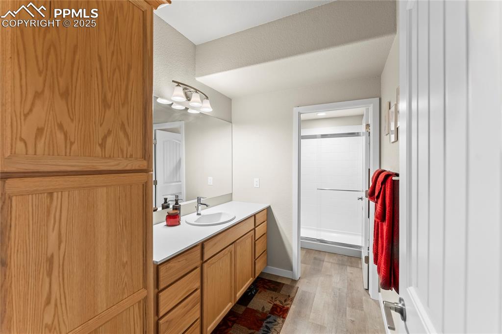 Image 45 of 50: Full bath featuring vanity, wood finished floors, and a stall shower
