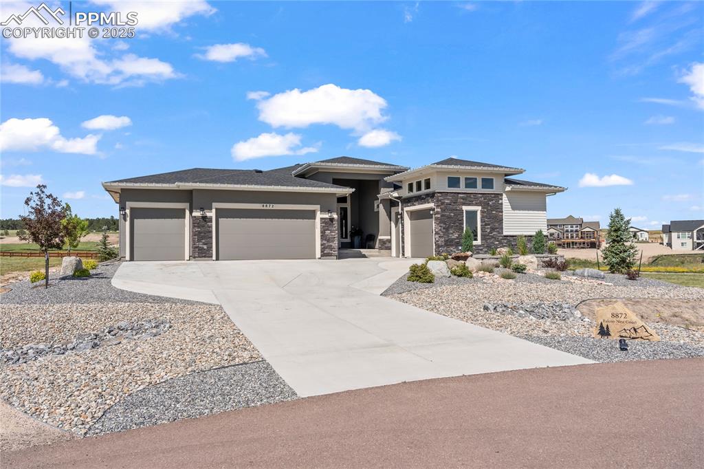 Image 6 of 50: Prairie-style home featuring stone siding, an attached garage, and concrete