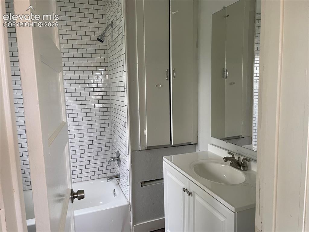 Image 12 of 16: Bathroom featuring a white subway tile shower surround, a built-in tub with