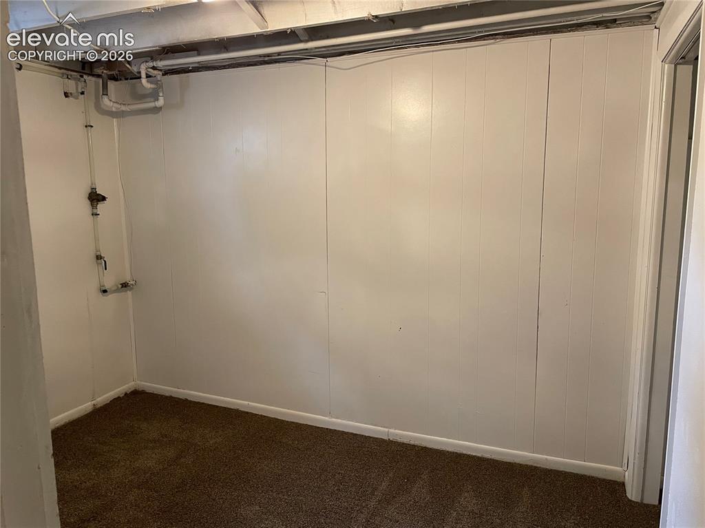 Image 16 of 16: Interior space featuring white vertical paneling and brown carpet flooring