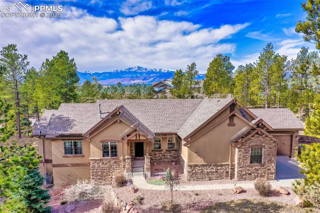 Caption: View of front of property featuring stucco siding, stone siding, and a mountain view