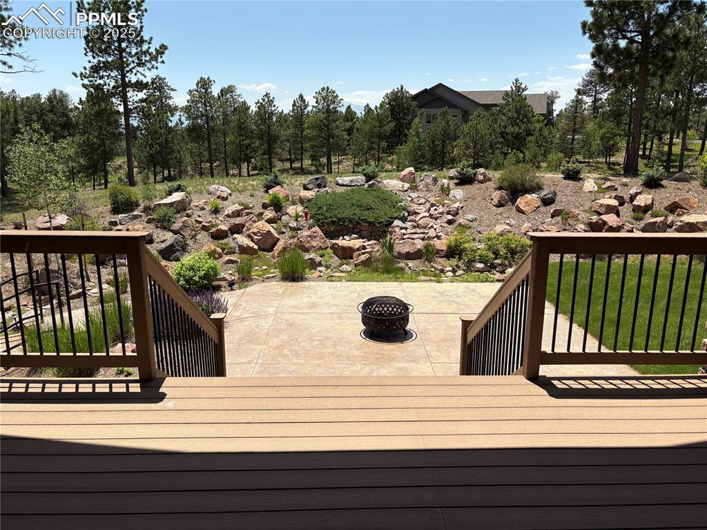 Image 11 of 48: Wooden terrace with a fire pit and a patio