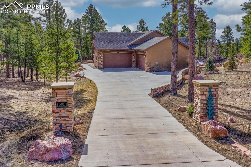 Image 14 of 48: View of front of house featuring stucco siding, stone siding, concrete driv