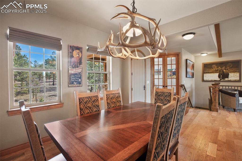 Image 23 of 48: Dining area with a notable chandelier, french doors, and light wood-type fl