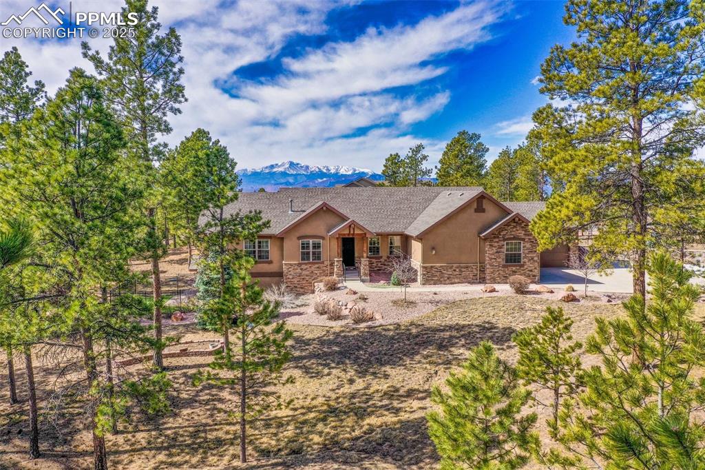Image 3 of 48: View of front facade with stone siding, stucco siding, and a mountain view