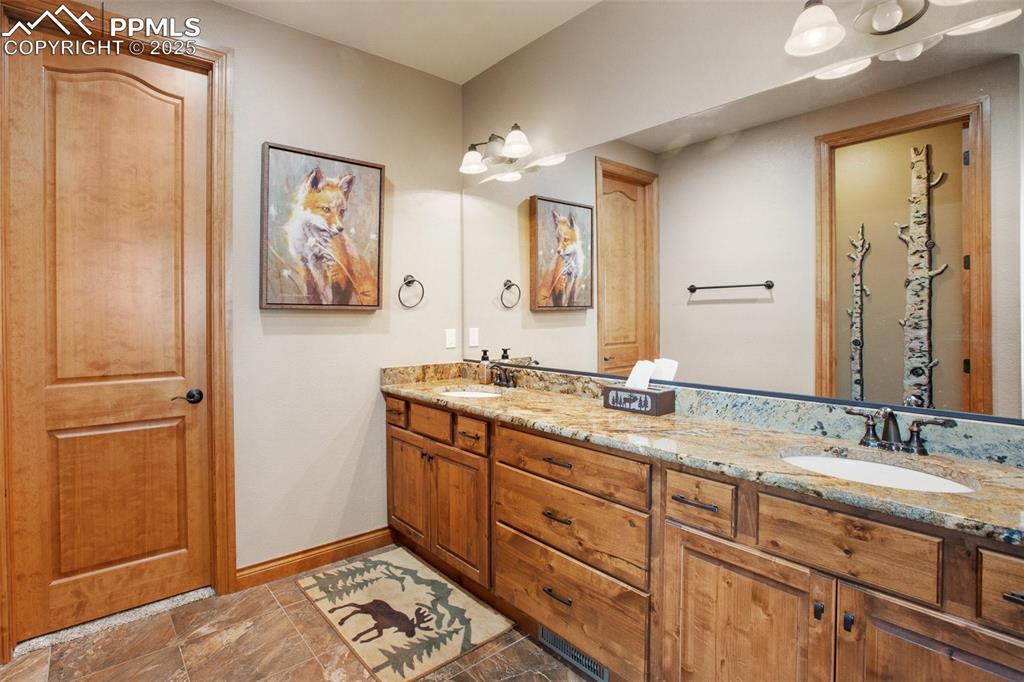 Image 32 of 48: Bathroom featuring double vanity, baseboards, and a sink
