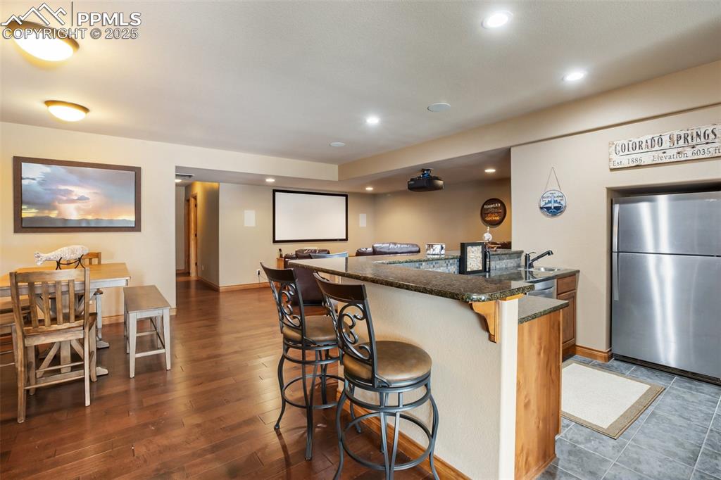 Image 36 of 48: Kitchen featuring recessed lighting, dark stone countertops, a kitchen brea