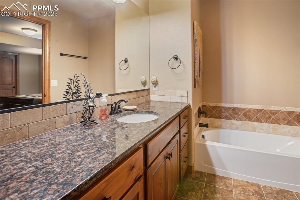 Image 42 of 48: Full bathroom with a garden tub, vanity, and tile patterned flooring