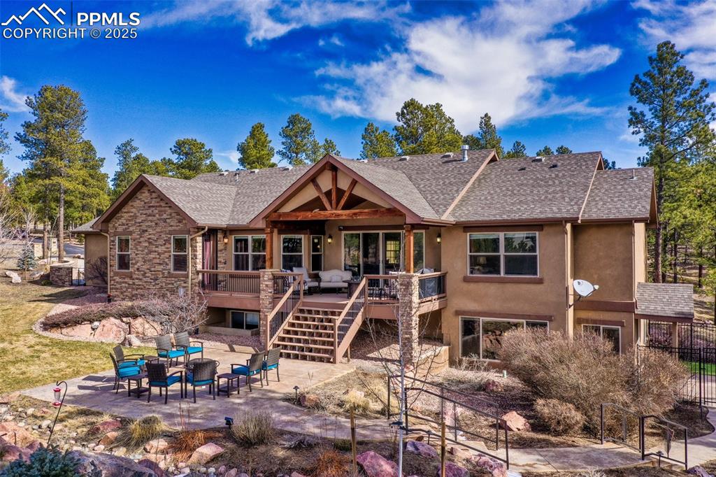 Image 7 of 48: Back of property featuring a wooden deck, a shingled roof, stairs, stucco s