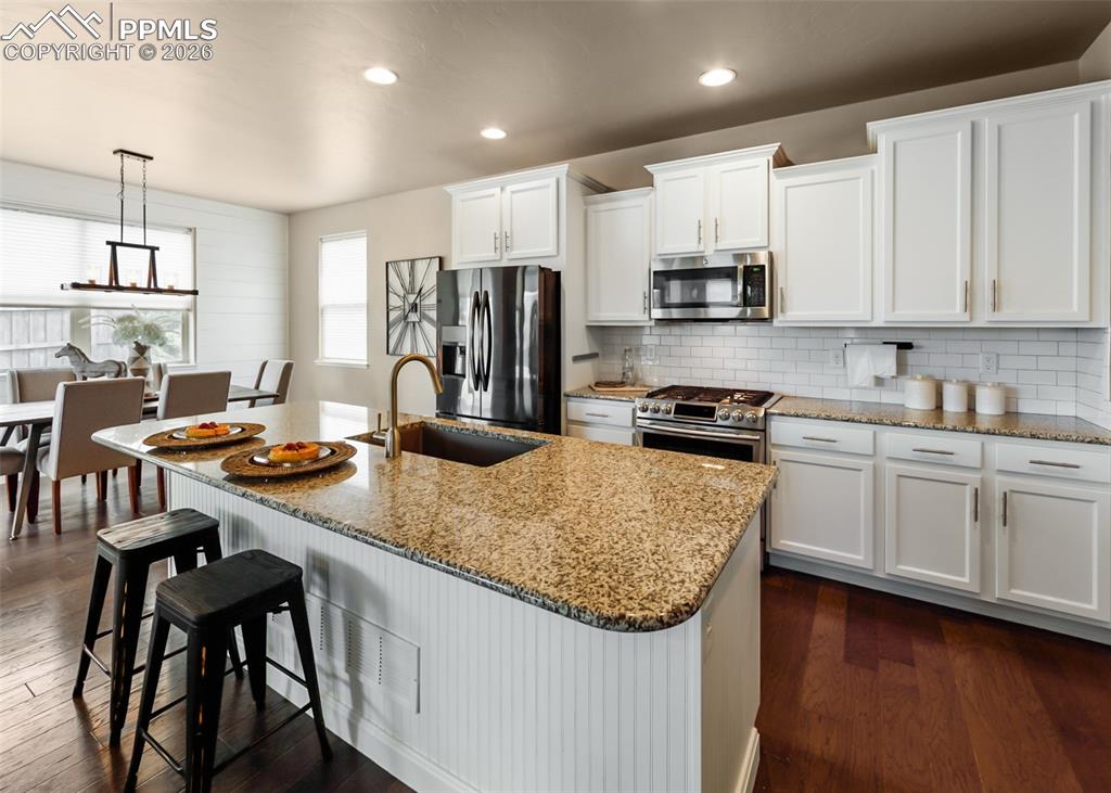 Image 13 of 50: Kitchen island with granite countertop, integrated sink, and bronze faucet