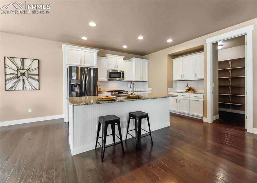 Image 14 of 50: Open-concept kitchen featuring an island with beadboard paneling, white cab