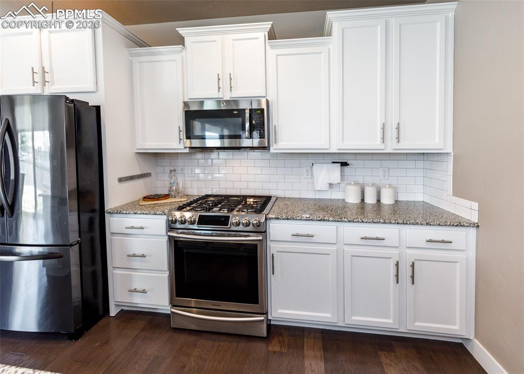Image 15 of 50: Kitchen featuring white shaker cabinetry, stainless steel appliances, speck