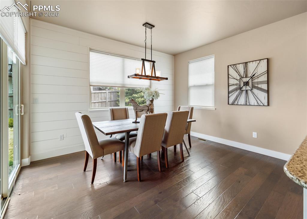 Image 19 of 50: Dining area featuring dark wood-finish flooring and a shiplap accent wall