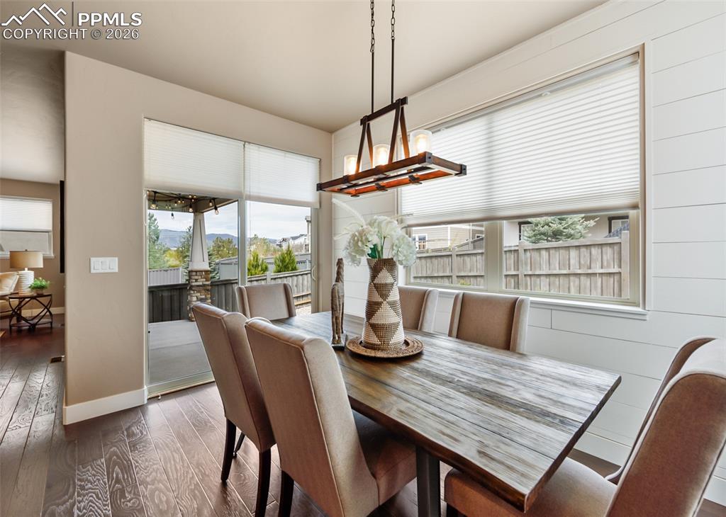 Image 20 of 50: Dining area featuring wood-finish flooring, shiplap accent wall, and a rust