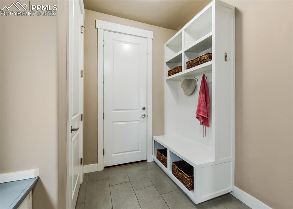 Image 27 of 50: Built-in mudroom storage unit featuring upper shelving, coat hooks, and a l