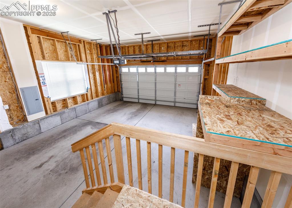 Image 28 of 50: Spacious garage with concrete flooring, overhead garage door, and built-in