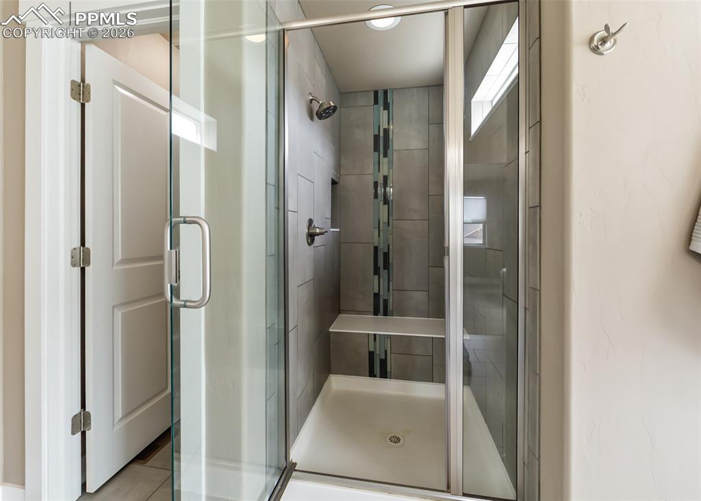 Image 40 of 50: Walk-in shower featuring a glass enclosure, gray tile surround with a decor