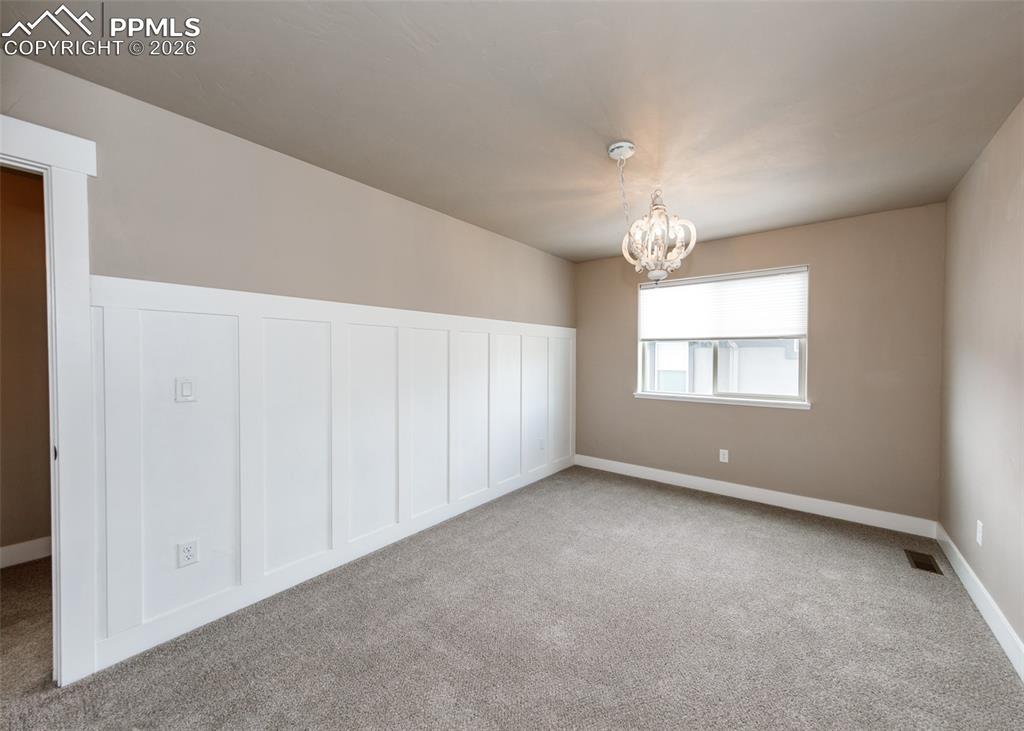 Image 42 of 50: Spacious room featuring board and batten wainscoting, neutral carpet, and a