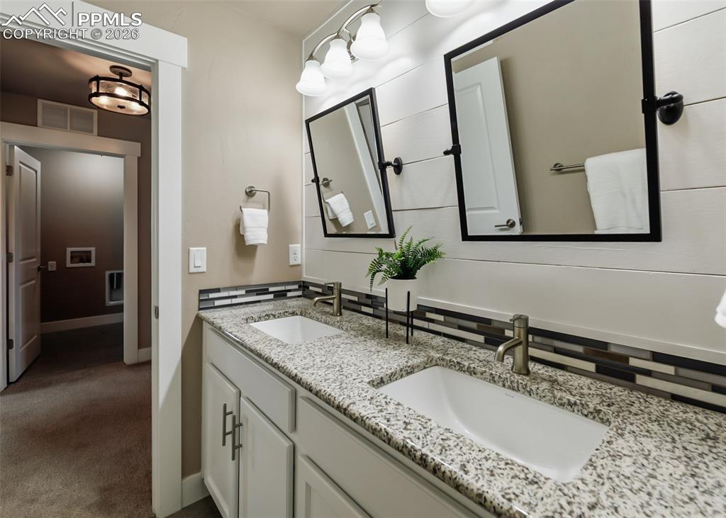 Image 45 of 50: Double vanity featuring granite countertops, undermount sinks, and brushed
