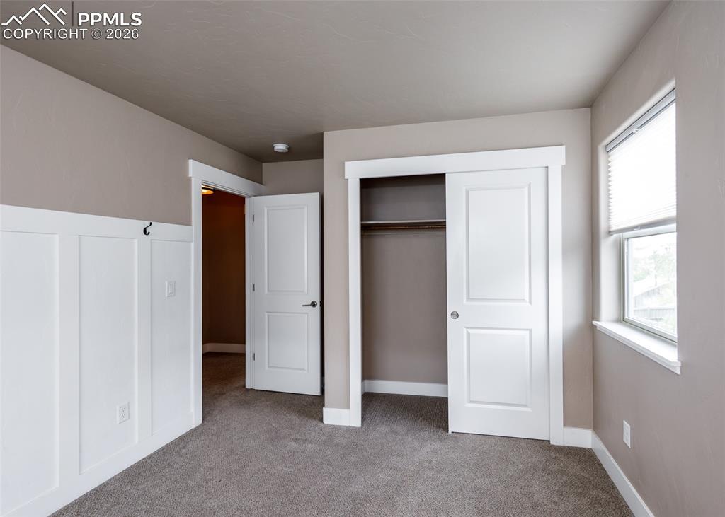 Image 47 of 50: Carpeted interior room featuring board and batten wainscoting, neutral wall