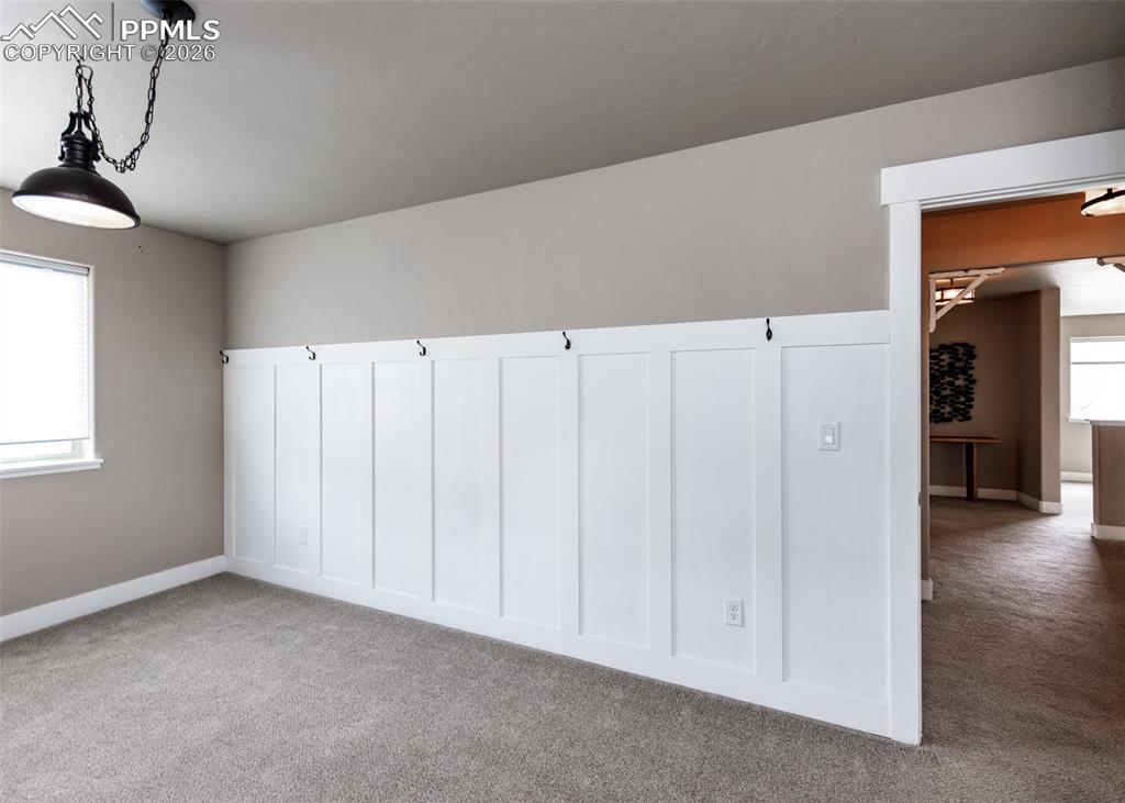 Image 48 of 50: Board and batten accent wall with hooks, neutral painted walls, and light g