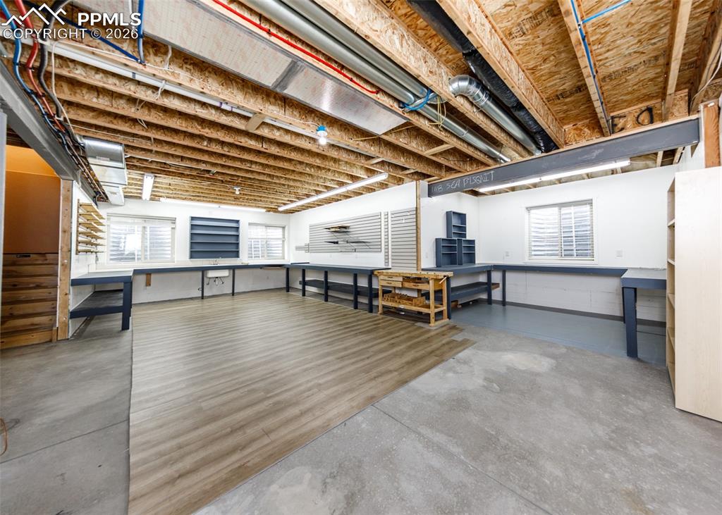 Image 49 of 50: Versatile basement workspace featuring concrete flooring, wood-finish floor