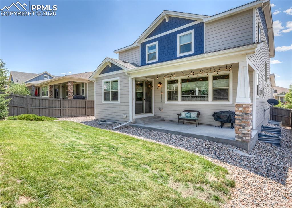 Image 50 of 50: Rear elevation featuring a covered patio with a stone-clad column, a slidin
