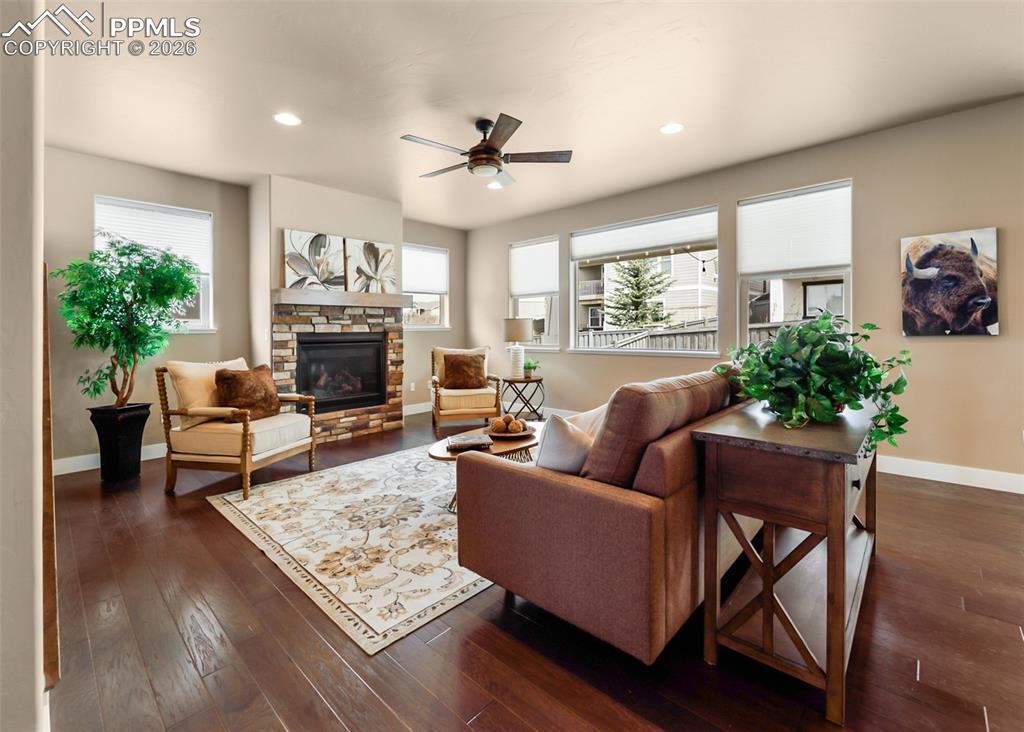 Image 8 of 50: Spacious living area featuring rich wood-finish flooring, a stone-surround