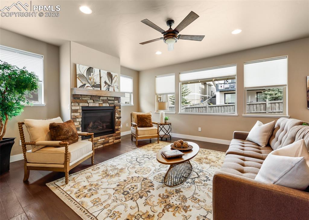 Image 9 of 50: Living area featuring a stone-clad fireplace with a wood mantel, dark wood-