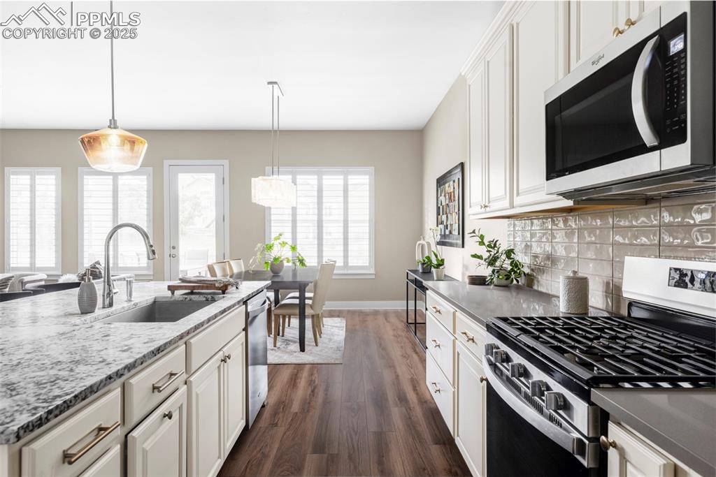 Image 10 of 44: Kitchen with appliances with stainless steel finishes, decorative light fix