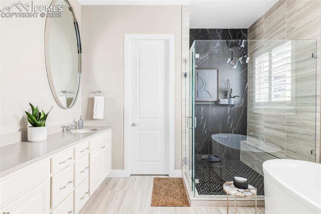 Image 23 of 44: Bathroom featuring a soaking tub, vanity, and a marble finish shower