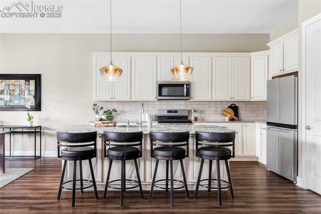 Image 6 of 44: Kitchen with stainless steel appliances, an island with sink, a kitchen bre