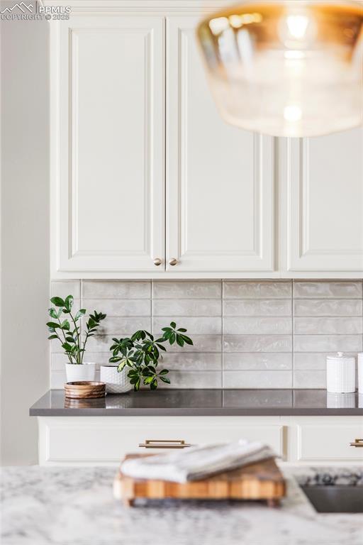 Image 8 of 44: Kitchen view of decorative backsplash, white cabinets, and dark stone count